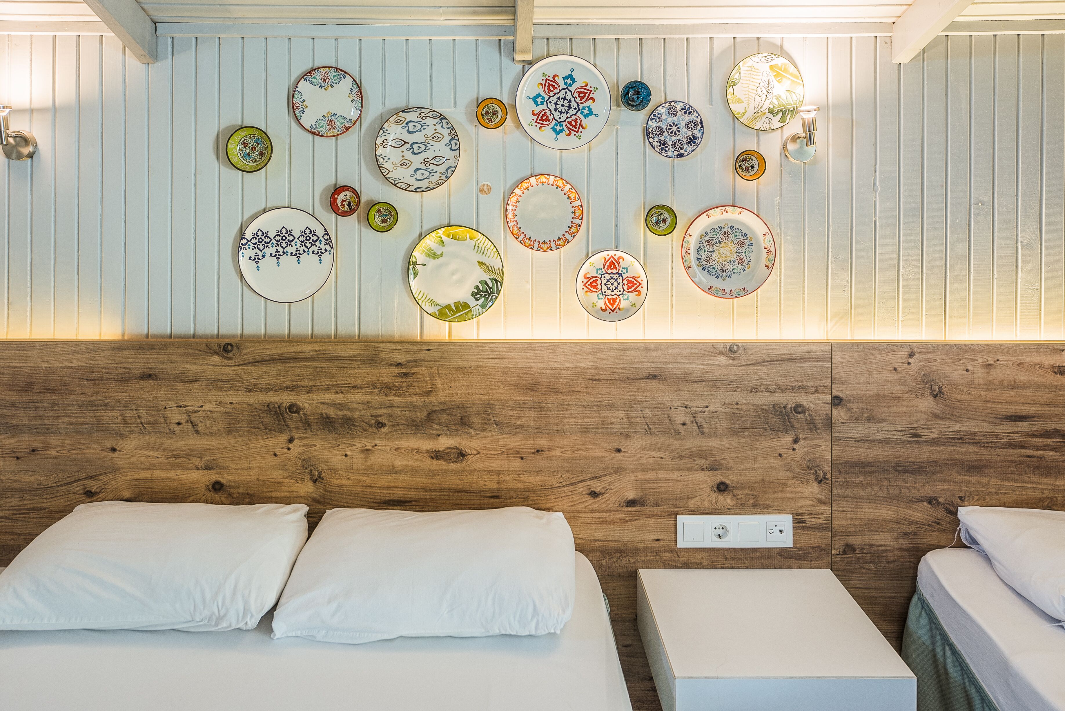 A hotel room with a wooden headboard, a wall-mounted light fixture, and a series of decorative plates.