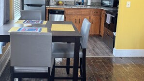 A compact kitchen with wooden cabinets, a refrigerator, a microwave, and a dining table with chairs. - The Queen Anne Inn (Augusta)