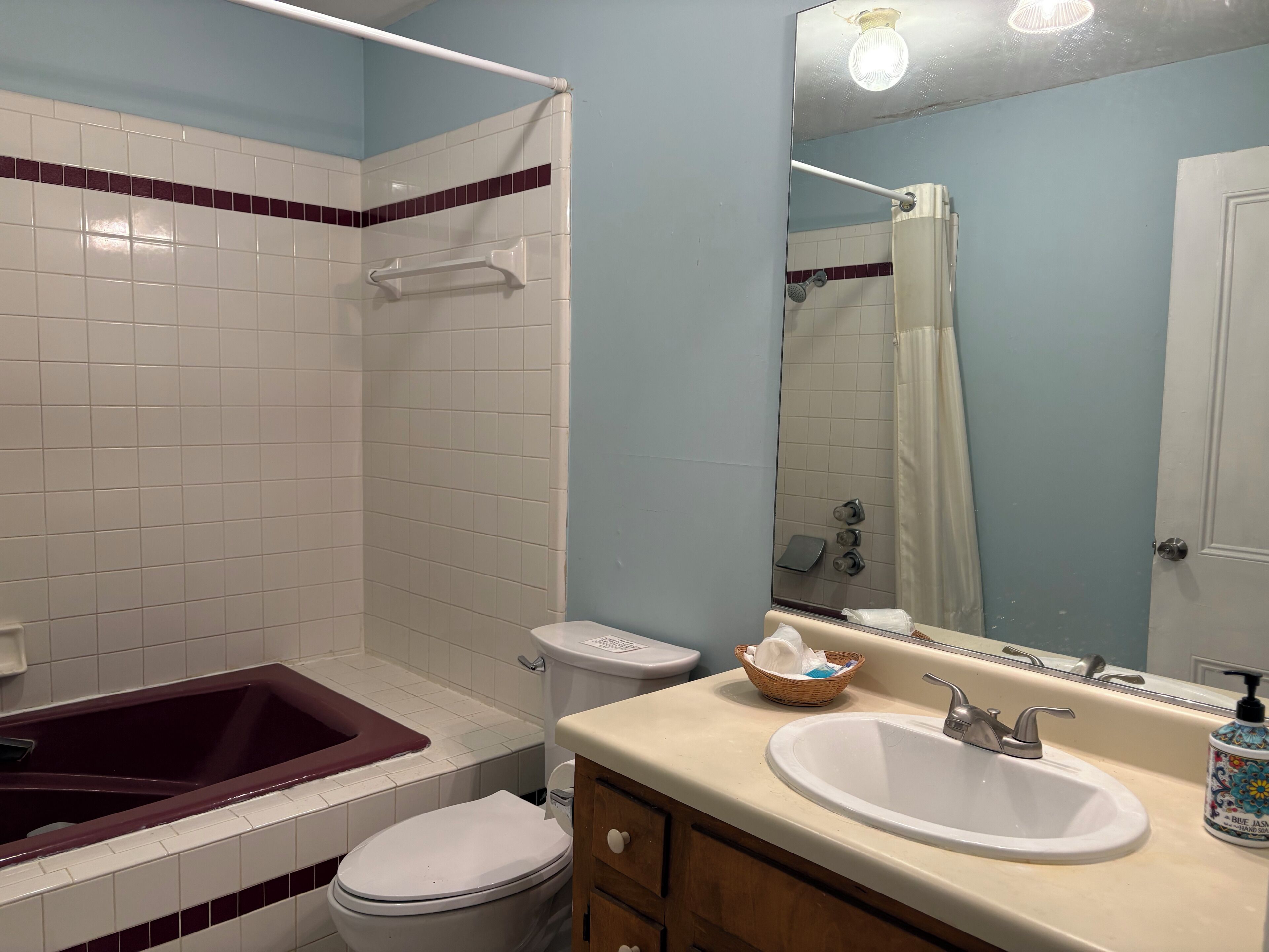 A bathroom with a bathtub, toilet, sink, and a mirror.