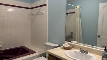 A bathroom with a bathtub, toilet, sink, and a mirror.