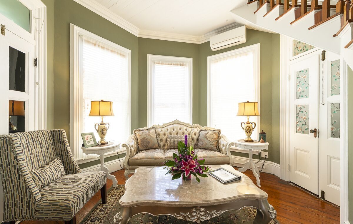 A living room with a patterned armchair, a tufted sofa, and a coffee table with a vase of flowers.