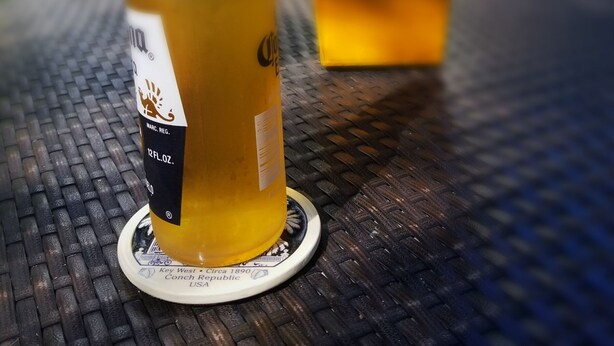 A bottle of Marc's Reserve 12 FL. OZ. on a coaster with a metal table. - Artist House Key West (Key West)