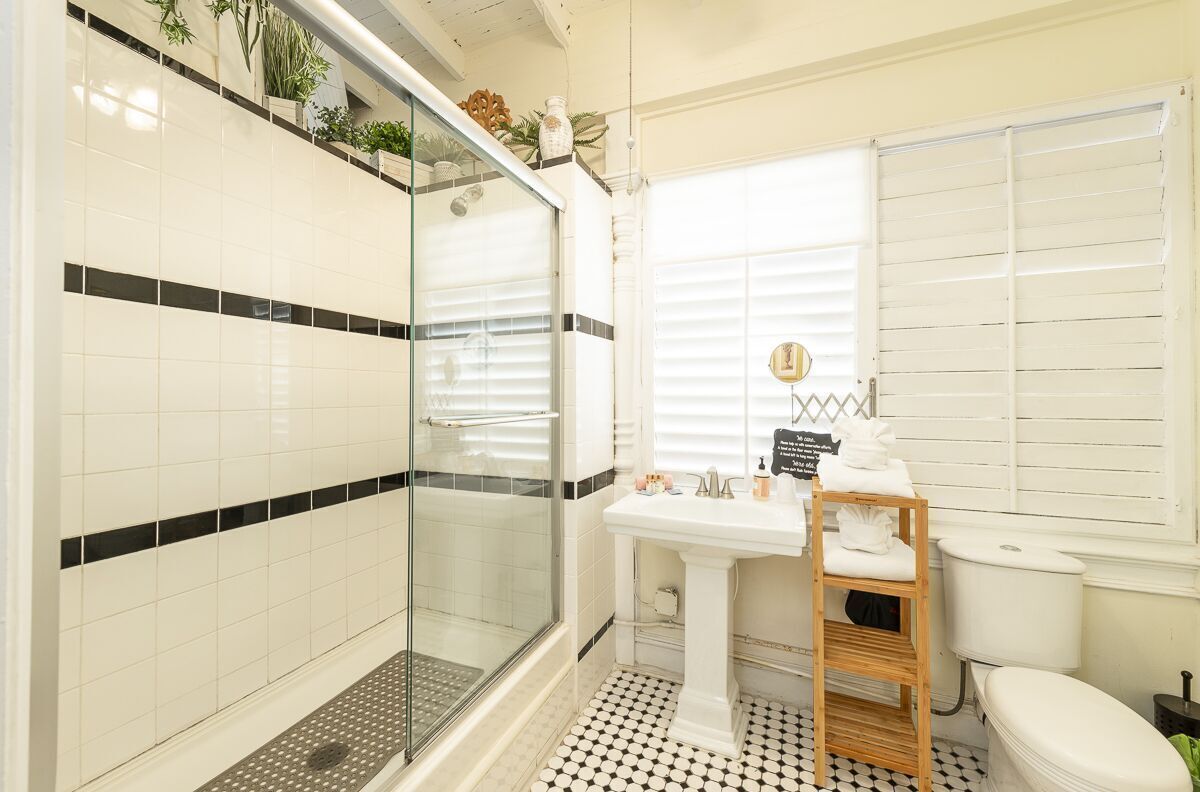 Un baño con mampara de vidrio, un lavamanos blanco y un inodoro.