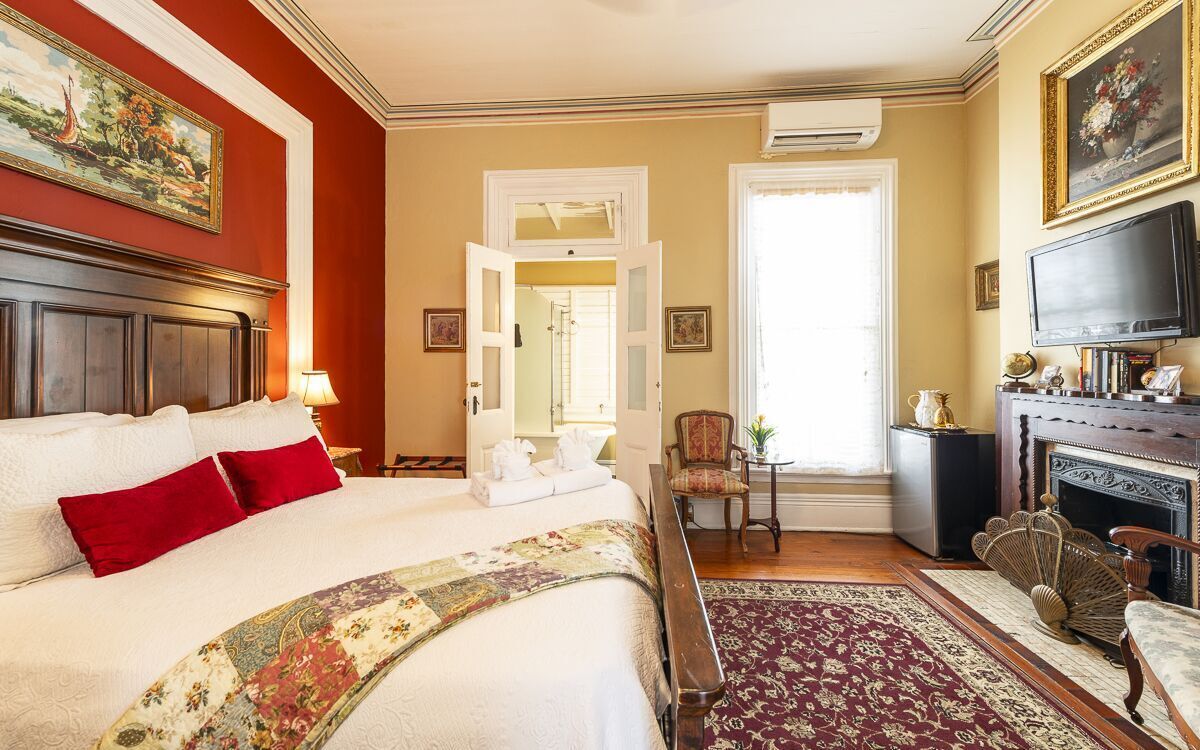 A hotel room with a large bed, a fireplace, a television, and a view of the outdoors.