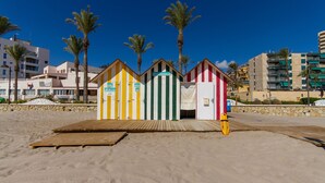 Una playa con cabañas de colores y palmeras.