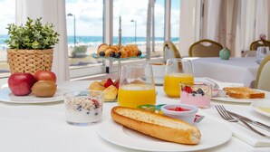 Una mesa de desayuno con cruasanes, fruta y vasos de jugo.