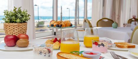 A breakfast table with croissants, fruit, and juice glasses.