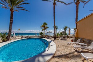 Una piscina al aire libre, sillones reclinables de piscina