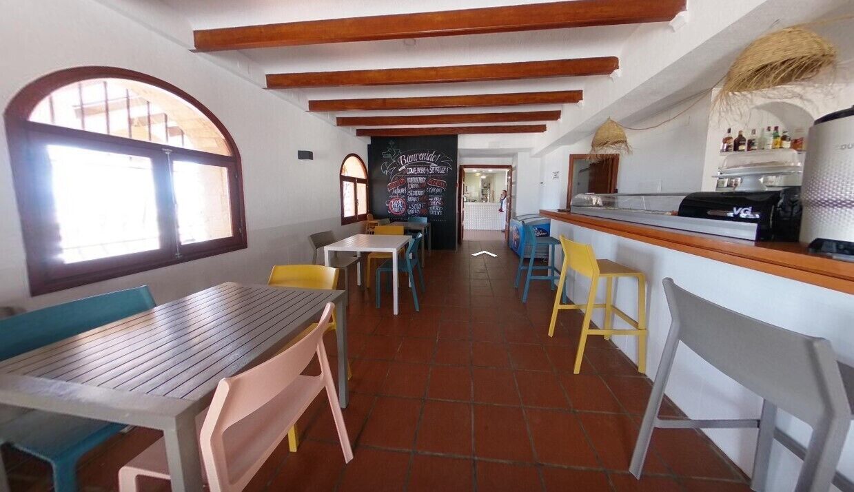 A restaurant with wooden beams, tiled floor, and colorful chairs.