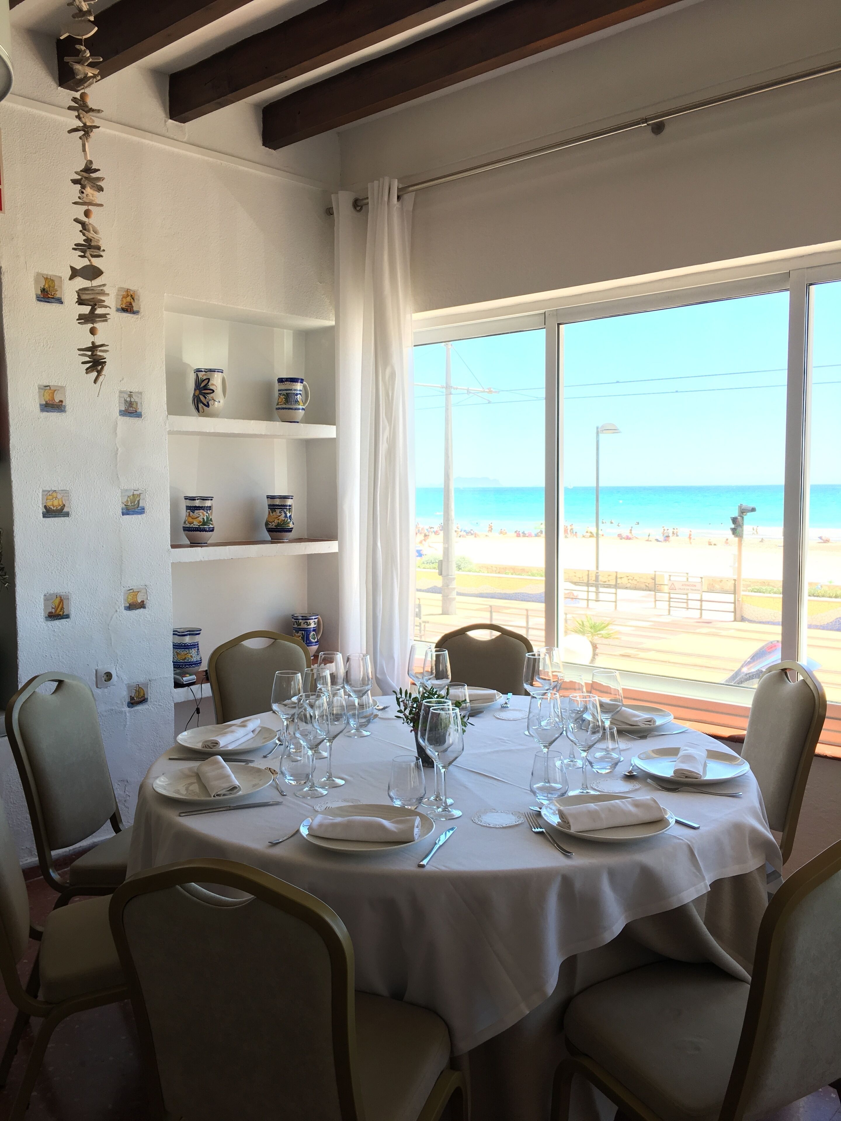Un comedor con una mesa preparada para seis personas, con vista a la playa.