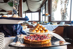 A buffet with various baked goods and desserts, including a large pie with berries.
