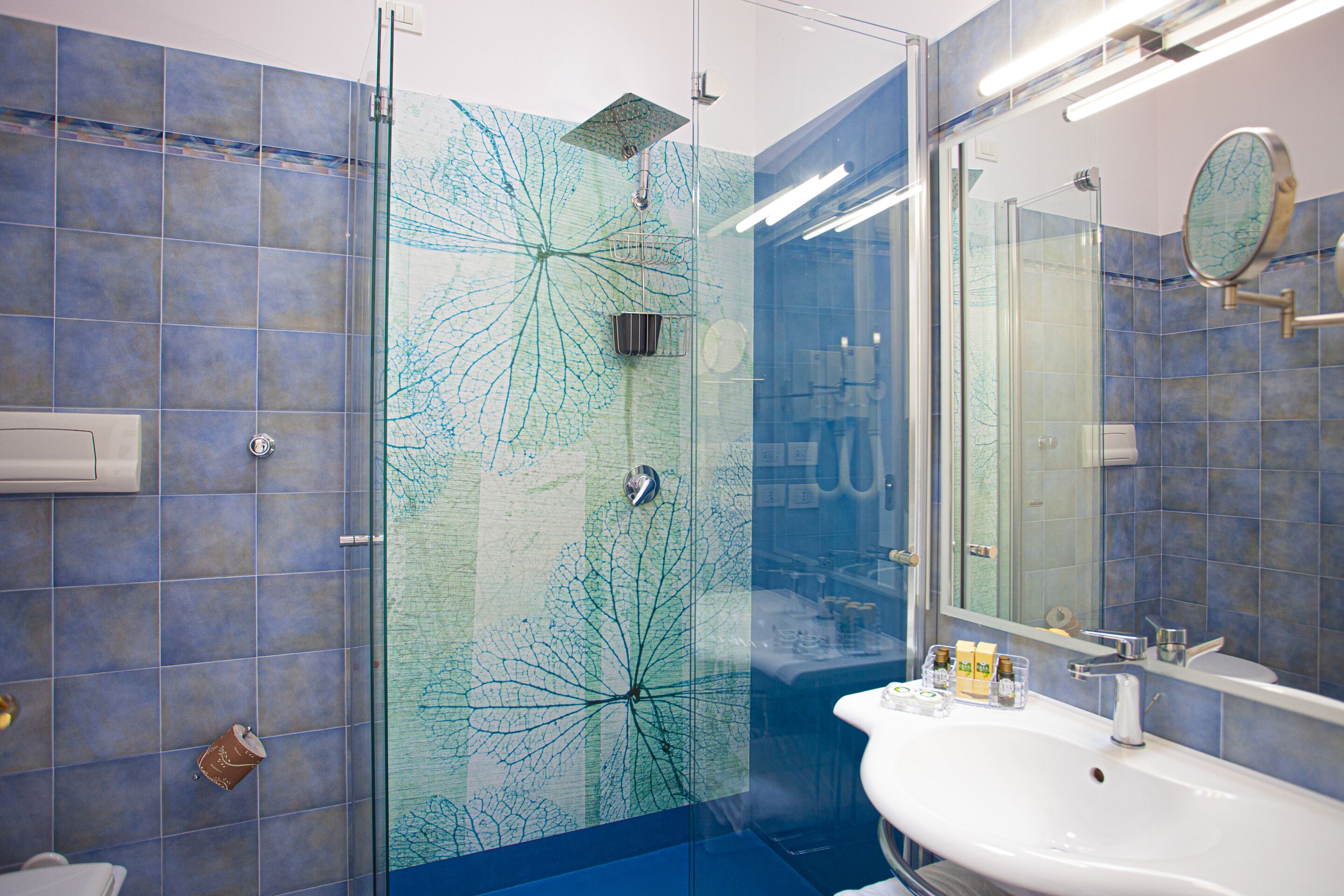 Une salle de bain avec une douche à parois de verre, un lavabo et un miroir.