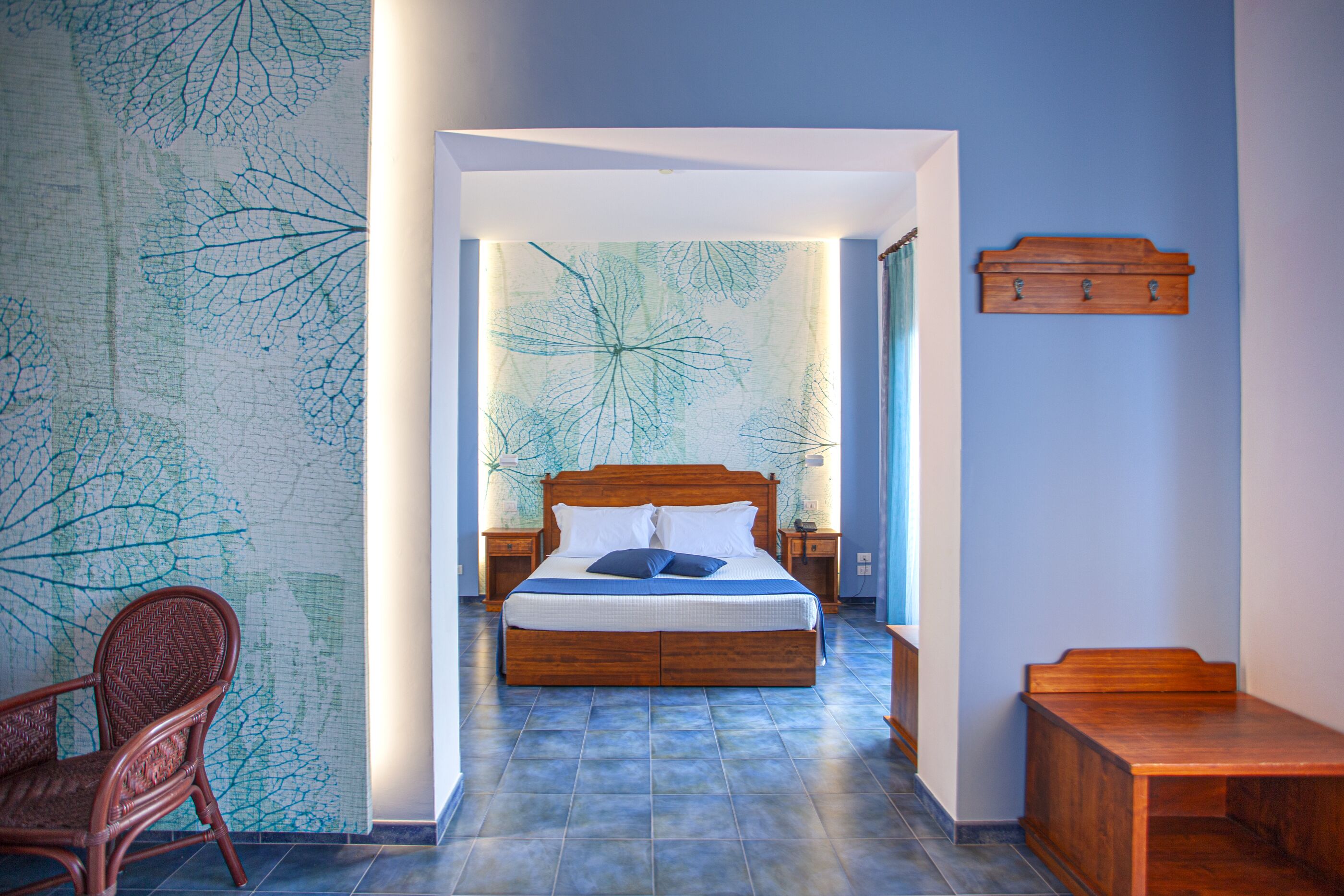 A bedroom with a wooden bed, a nightstand, a chair, and a wooden bench.
