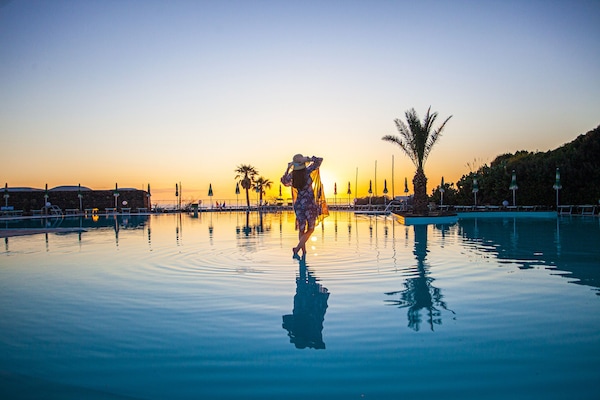 Una piscina al aire libre, sombrillas, sillones reclinables de piscina