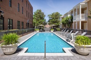 A rectangular pool with a metal safety railing in the center, surrounded by lounge chairs and potted plants. - Residence Inn by Marriott Savannah Downtown/Historic District (Savannah)