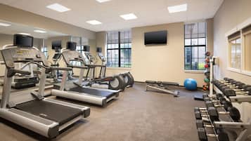 Un gimnasio con cintas de correr, elípticas y mancuernas.