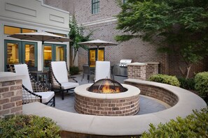 Un patio exterior con un brasero, asientos y una parrilla.