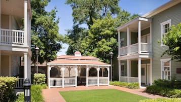 A courtyard with a gazebo, surrounded by buildings with balconies and a well-maintained lawn.