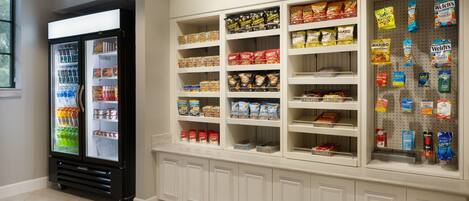 A grocery store interior with refrigerated cases and shelves stocked with snacks and beverages.
