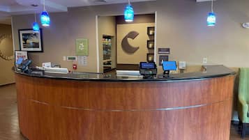 A reception desk with a wooden finish, a digital display, and a cash register.