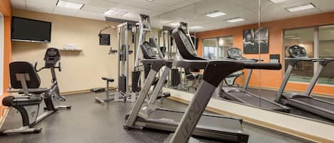 Un gimnasio con cintas de correr, elípticas y equipo de pesas.