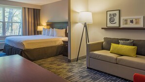 A hotel room with a bed, a desk, a sofa, a lamp, and framed pictures on the wall. - Country Inn & Suites by Radisson, Doswell (Kings Dominion), VA (Doswell)