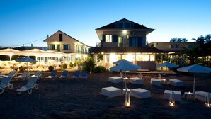 A beachside hotel with outdoor seating, umbrellas, and lounge chairs. - Aggelos Hotel (Messini)