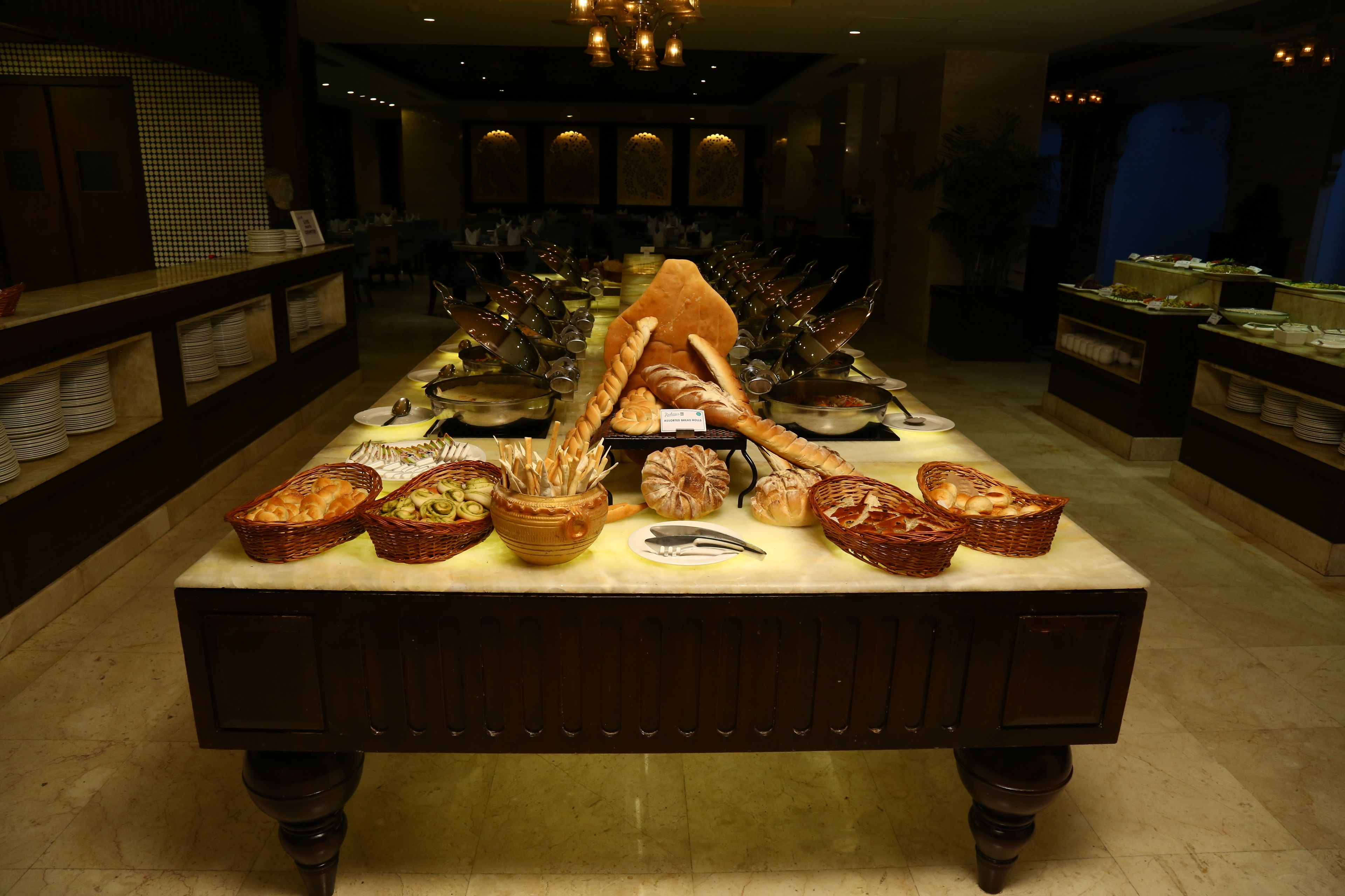 A buffet table with various food items and bread displayed.
