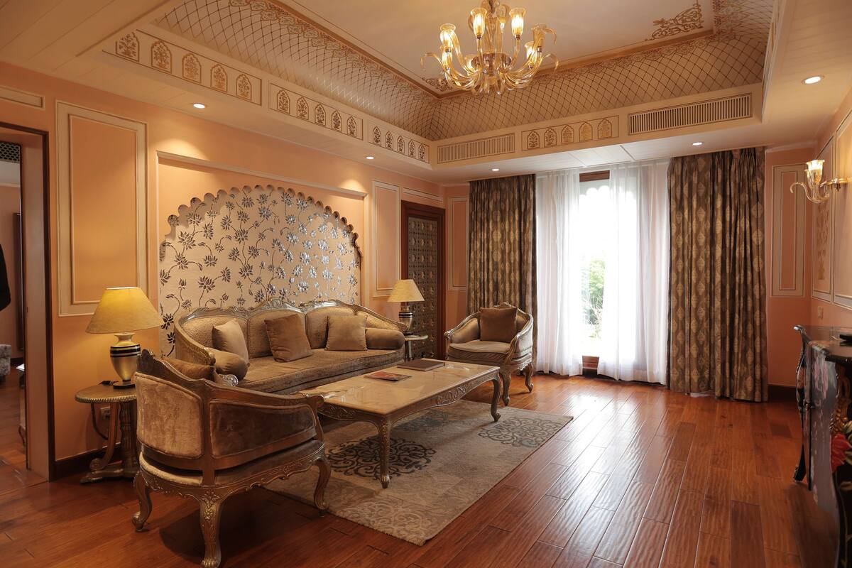 Ein luxuriöses Wohnzimmer mit einer Couch, Sesseln, einem Couchtisch und einer Wand mit Muster.