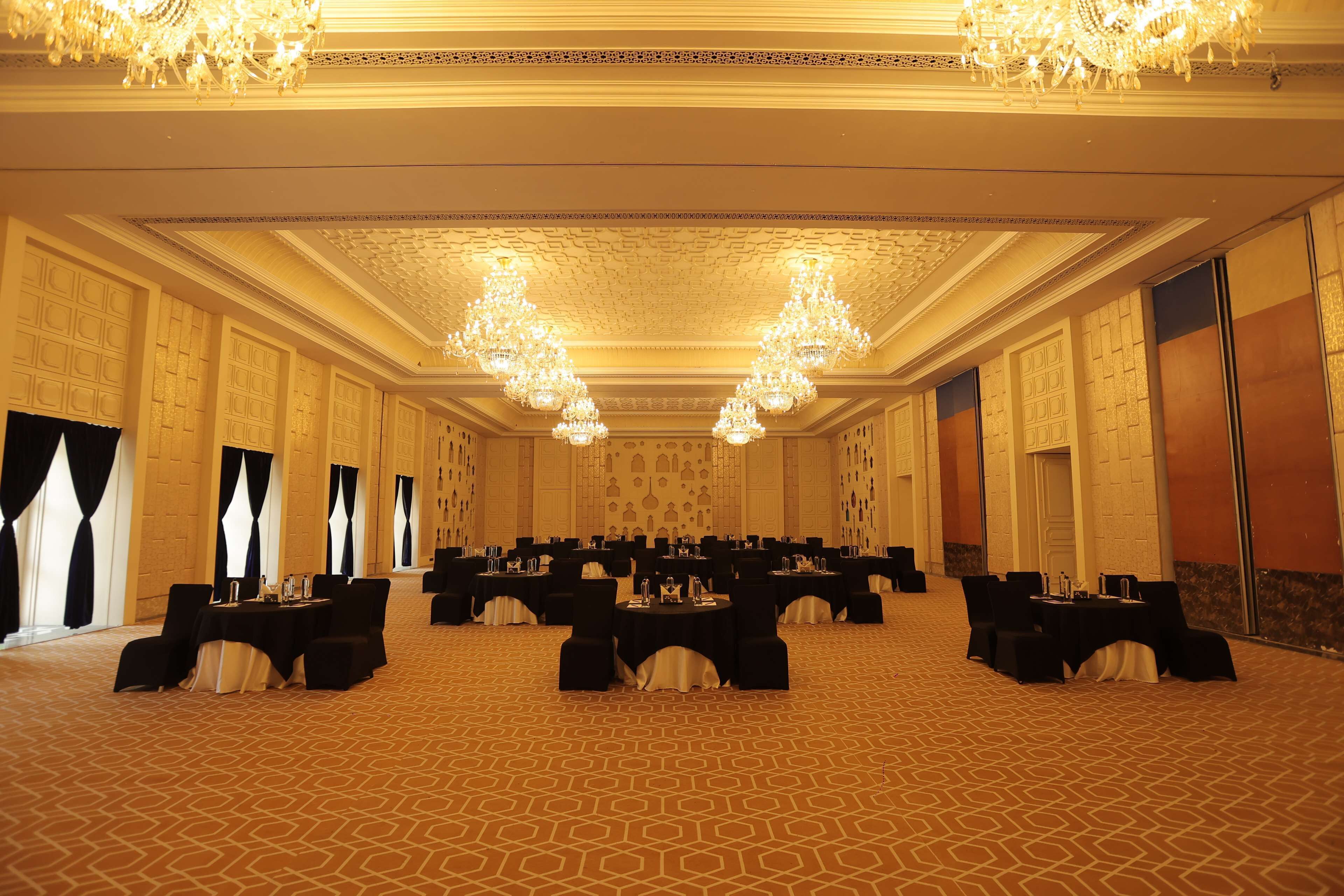 A banquet hall with multiple round tables, black tablecloths, and chairs.