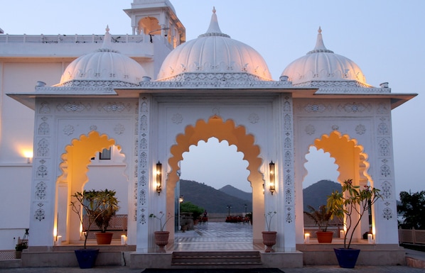 A traditional building with ornate arches and domes, a staircase leading to an upper level, and potted plants at the entrance. - Radisson Blu Udaipur Palace Resort & Spa (Udaipur)