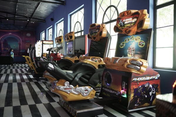 An arcade with racing game machines, checkered floor, and large windows.