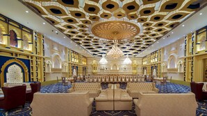 Un lobby de hotel lujoso con candelabros ornamentados, asientos confortables y diseños intrincados en las paredes.