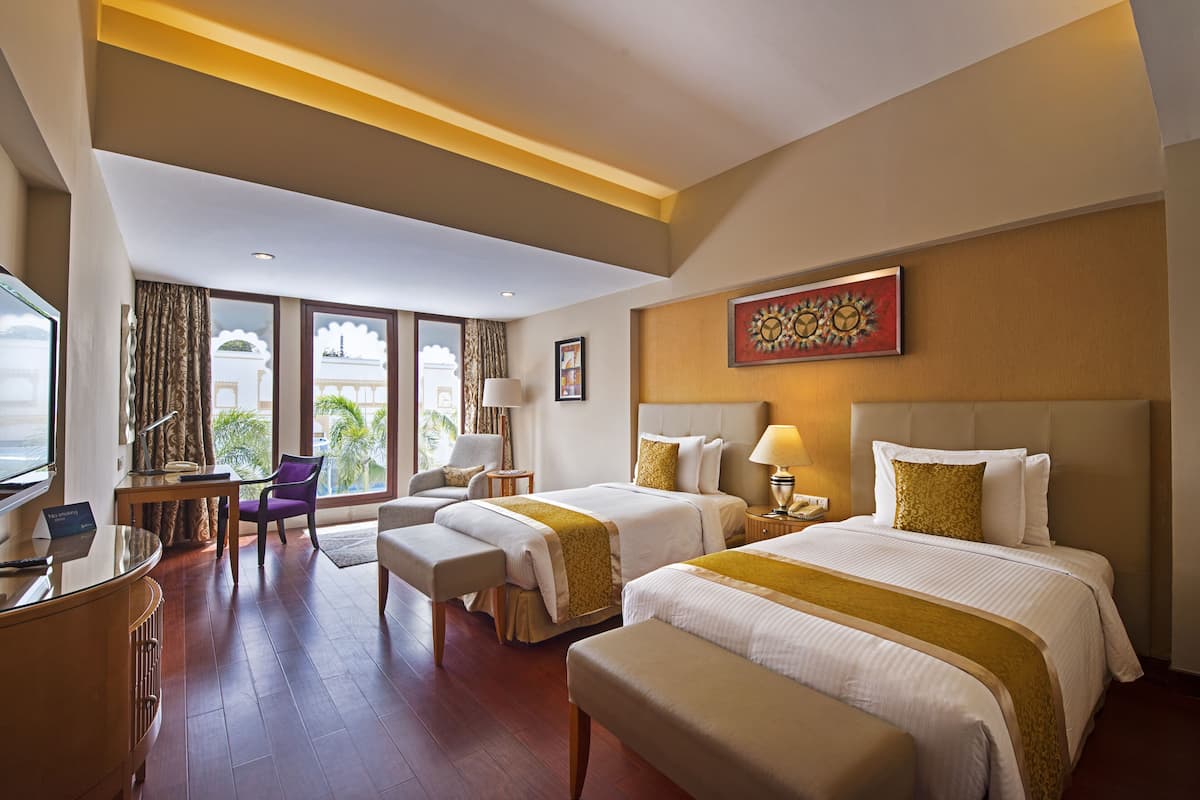 Ein Hotelzimmer mit zwei Betten, einem Schreibtisch, einem Stuhl und einem großen Fenster.