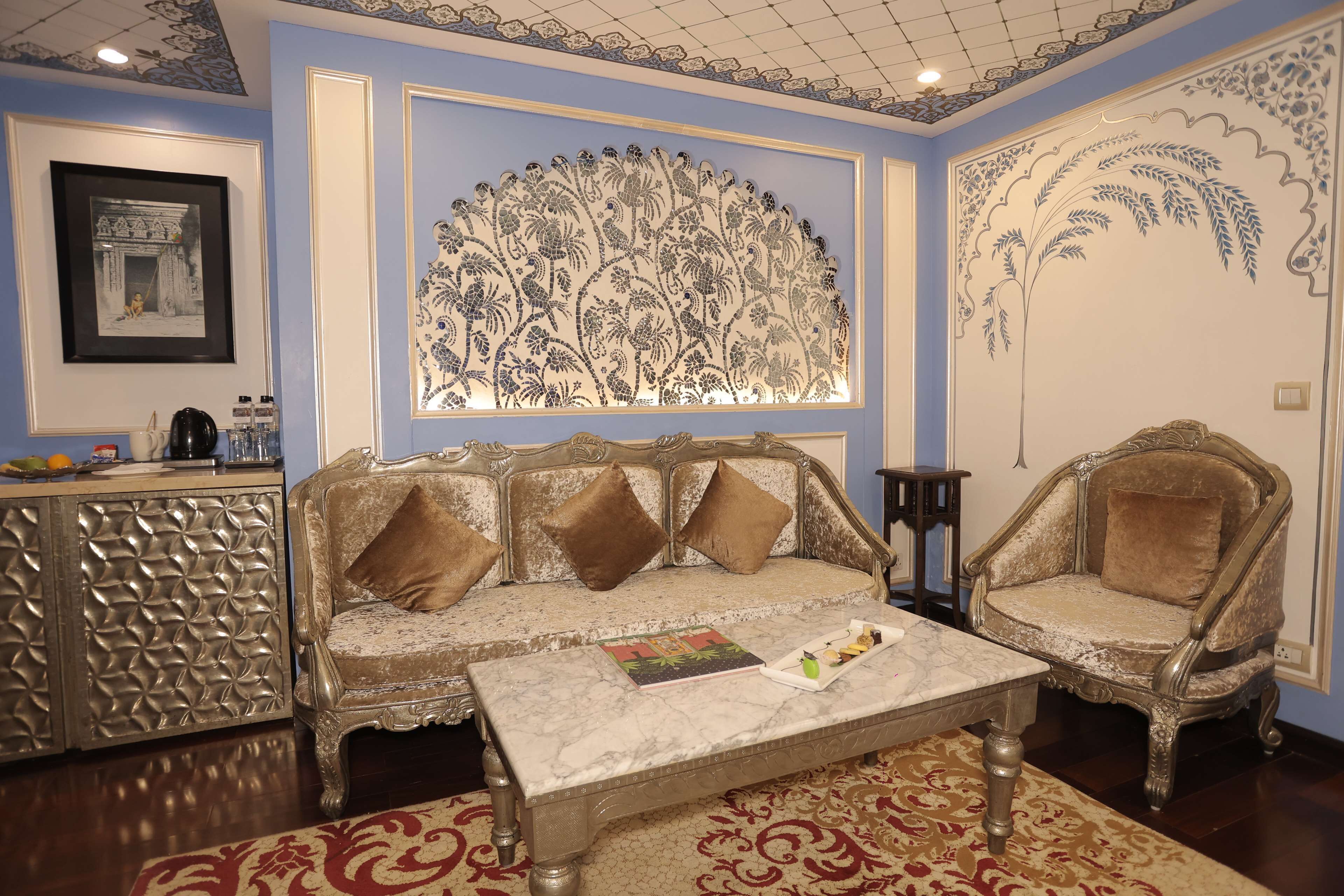 A room with a sofa, two armchairs, a coffee table, and a decorative wall panel.
