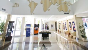A spacious lobby with a large world map on the ceiling, a polished floor, and a reception desk. - Quórum Cordoba Hotel - Resort Urbano (Córdoba)