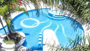 A circular pool with a central island and surrounding palm trees. - Quórum Cordoba Hotel - Resort Urbano (Córdoba)