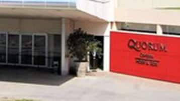 Un bâtiment moderne doté d’une entrée couverte et d’une enseigne rouge.