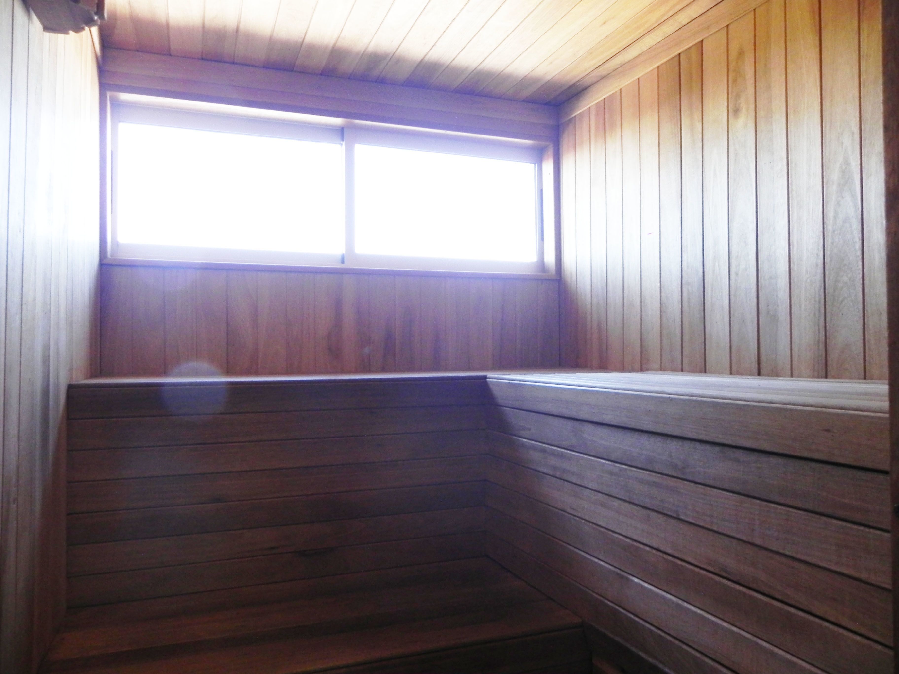 A corner of a room with wooden walls and a window.