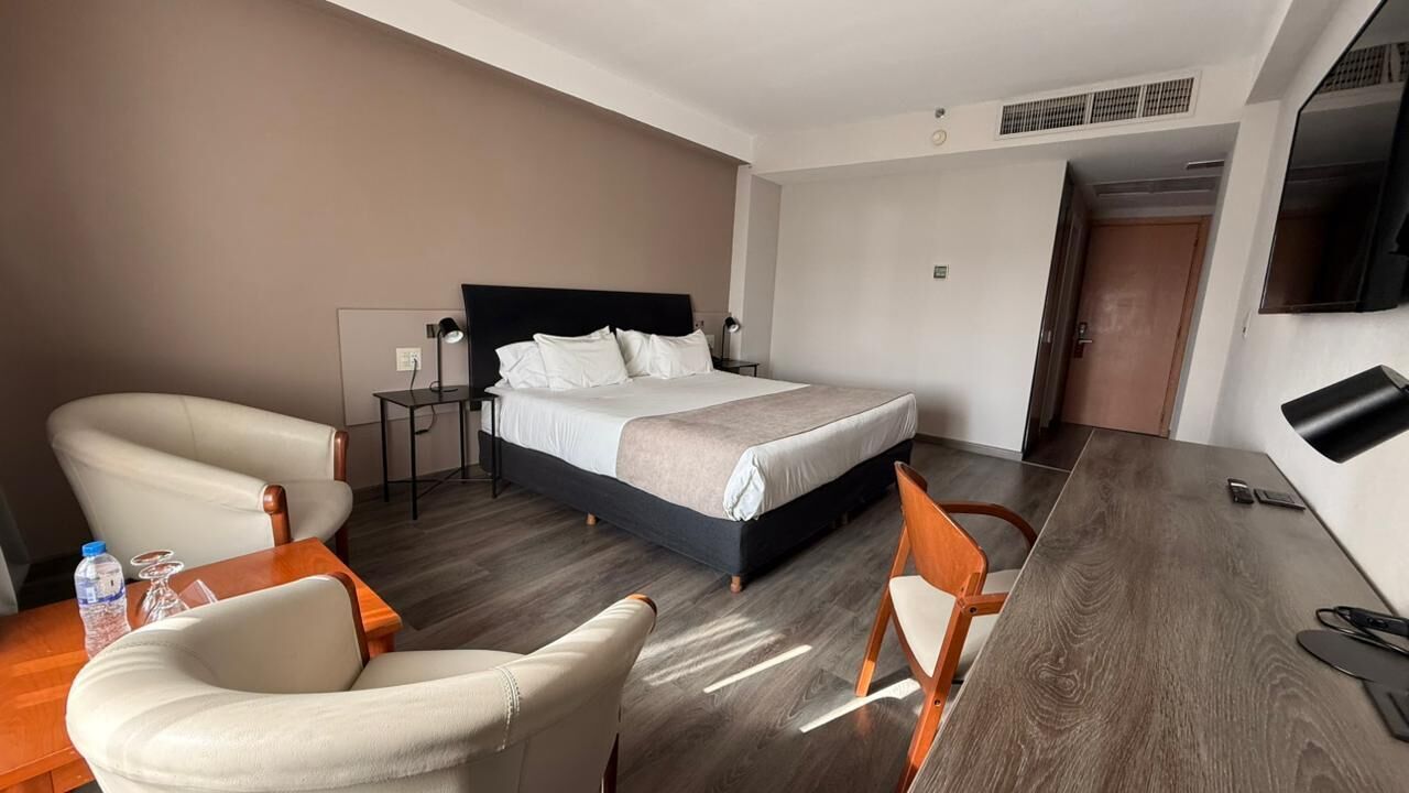 Una habitación de hotel con cama, escritorio, silla y televisión.
