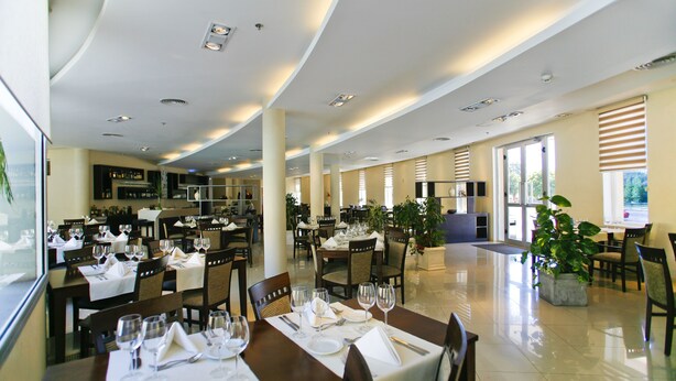 A spacious restaurant with multiple dining tables set for guests, large windows allowing natural light, and a clean, modern interior design. - Quórum Cordoba Hotel - Resort Urbano (Córdoba)