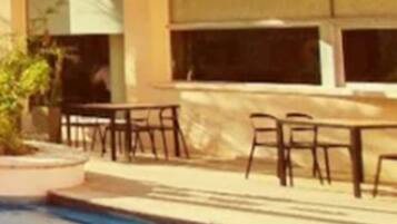 A building with a pool area, outdoor seating, and palm trees.