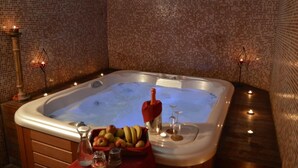 Un jacuzzi con pared de azulejos, velas y un frutero.