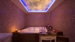 Un baño moderno con una bañera independiente, una mesita con artículos de aseo y una lámpara en el techo.