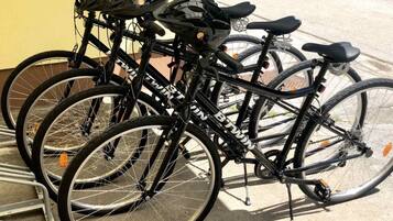 En rad cyklar med hjälmar och sadlar, parkerade utanför en byggnad.