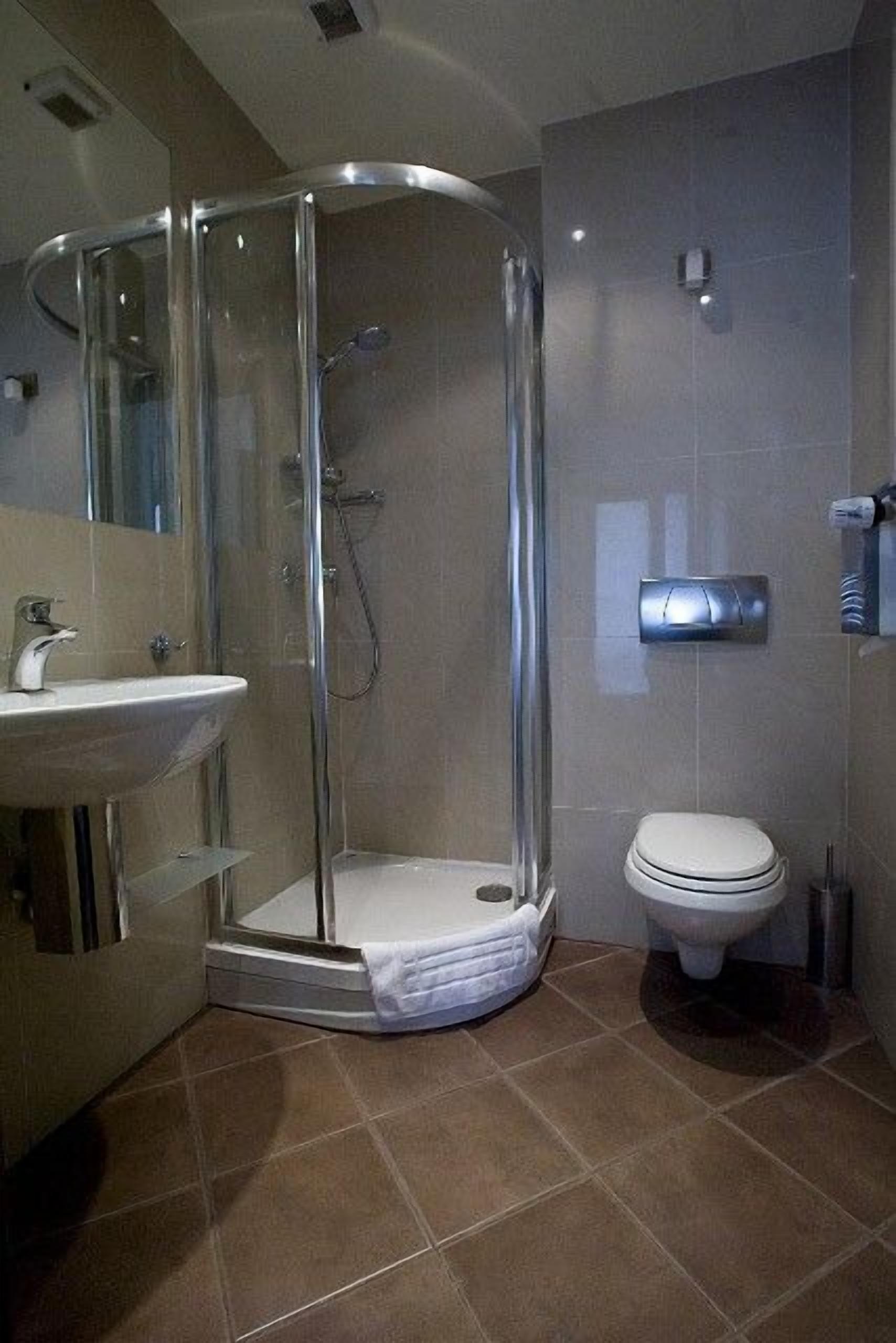 Une salle de bain moderne avec une douche à parois de verre, un lavabo blanc et des toilettes.