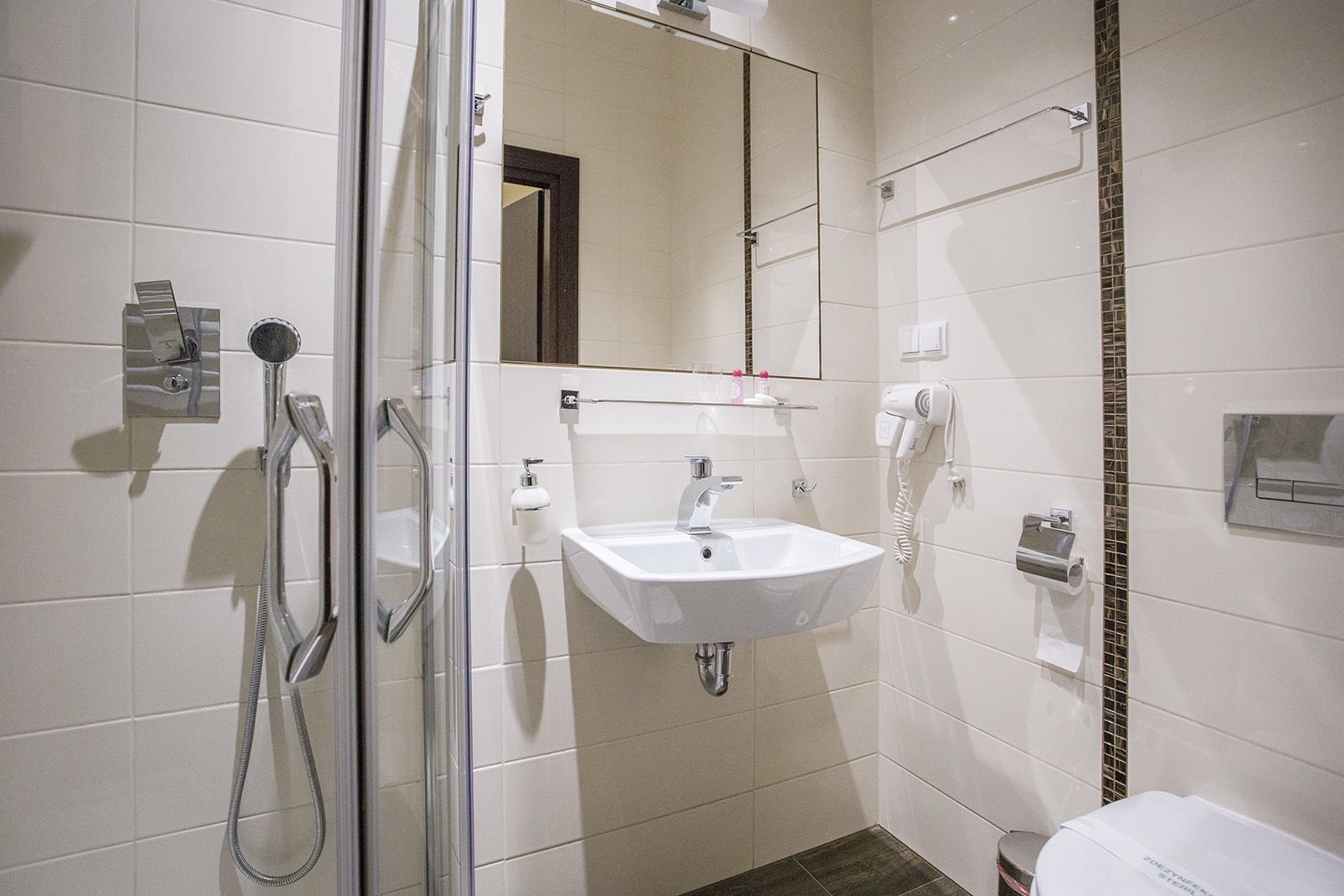A bathroom with a glass shower enclosure, a white sink, and a mirror above it.