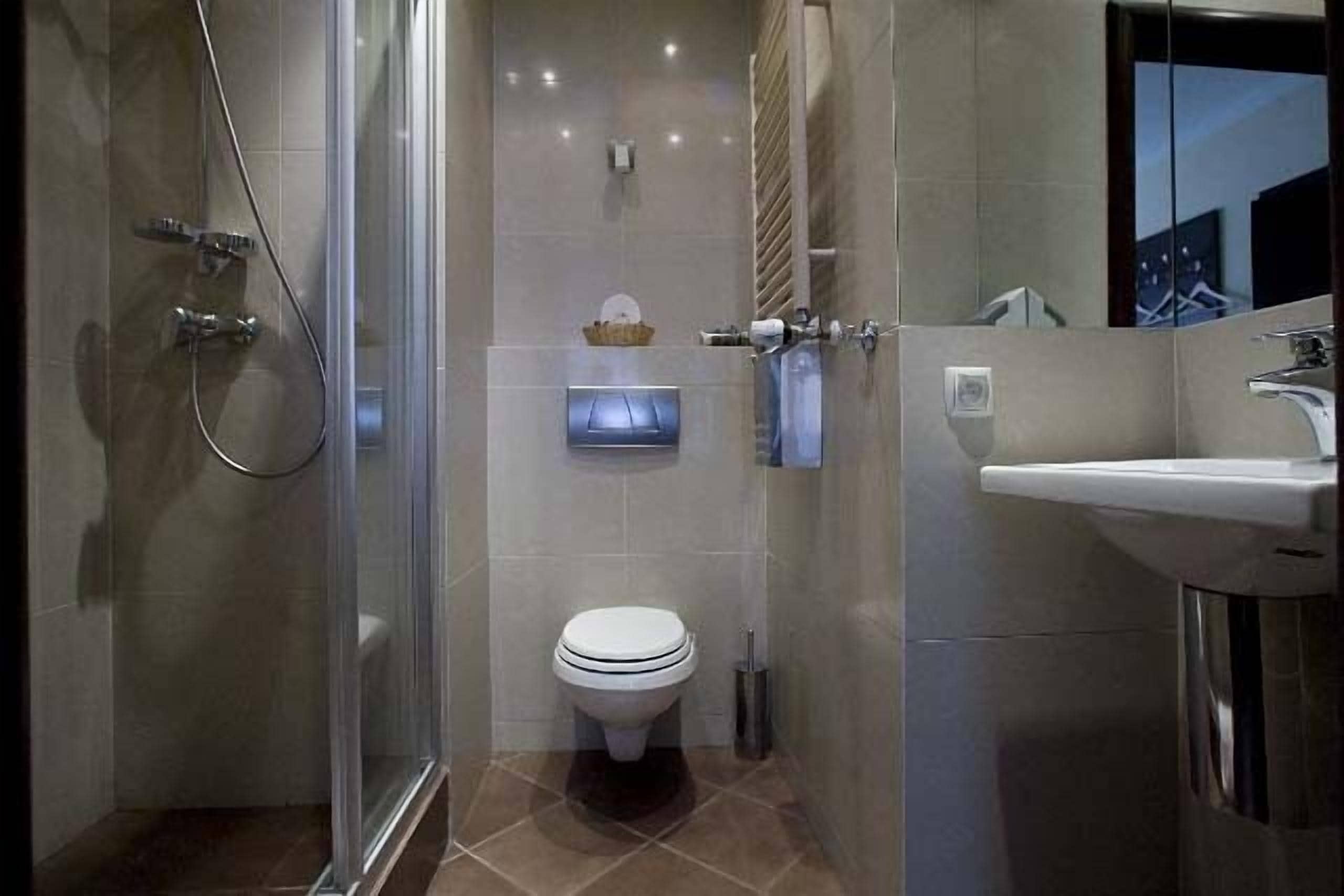 Un bagno moderno con box doccia in vetro, un WC e un lavandino.