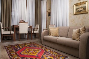 A living room with a beige sofa, two armchairs, a coffee table, and a patterned rug.