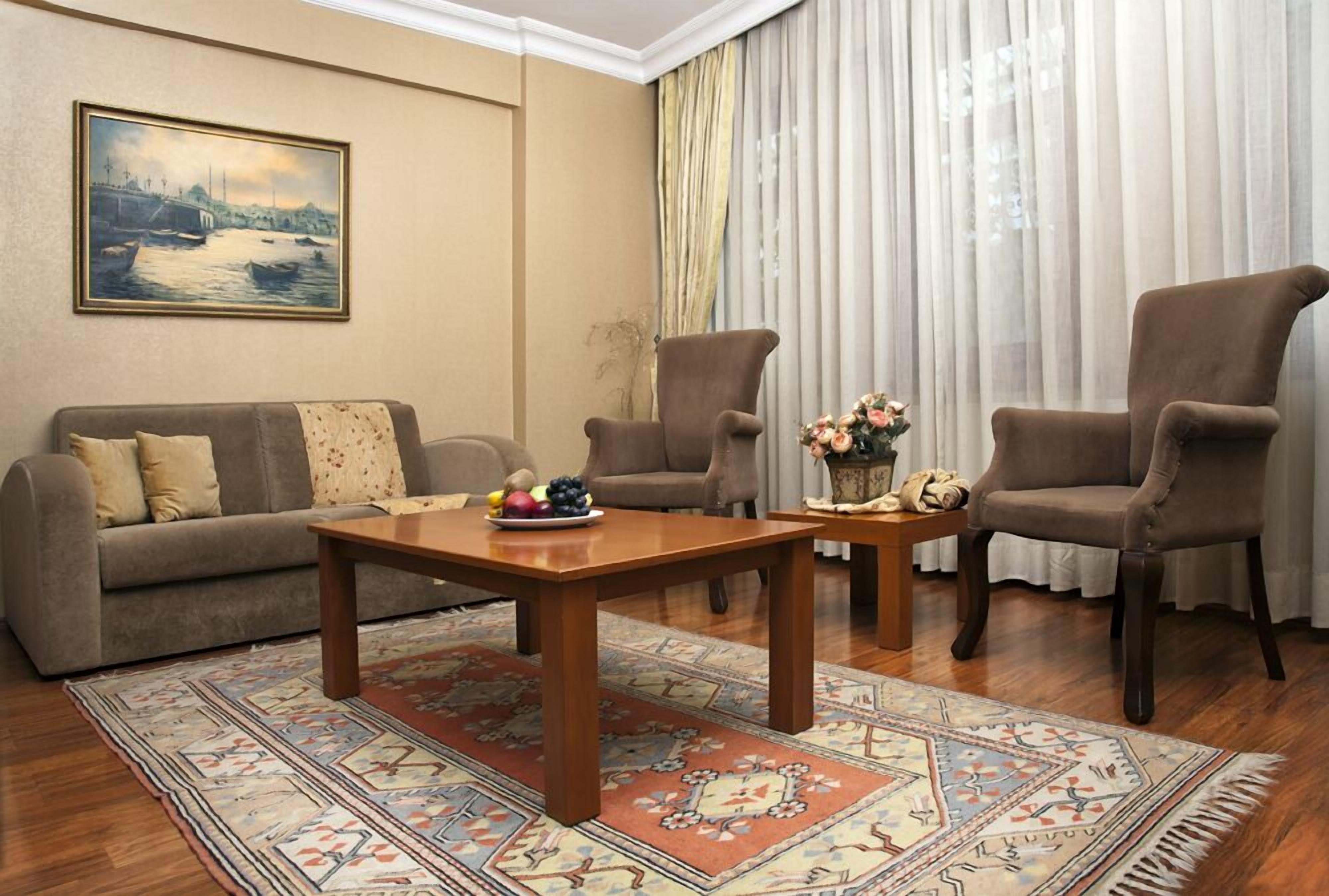 A living room with a sofa, two armchairs, a coffee table, and a rug.